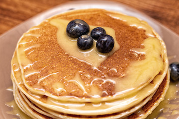Pancakes with blueberries and honey on the dark brown wooden background