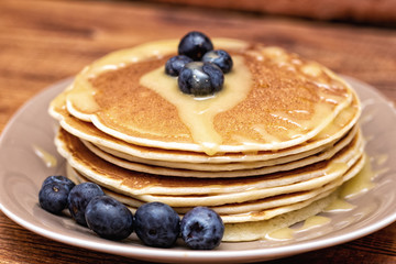 Pancakes with blueberries and honey on the dark brown wooden background