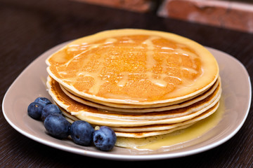 Pancakes with blueberries and honey on the dark brown wooden background