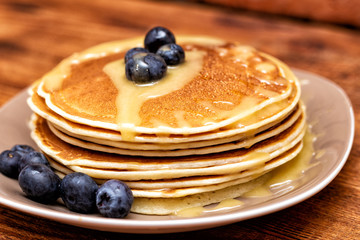 Pancakes with blueberries and honey on the dark brown wooden background