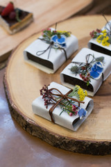 Brownies wrapped in papers with flower decoration all on wooden platter