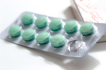 green soft gel pills in blister pack on white background.