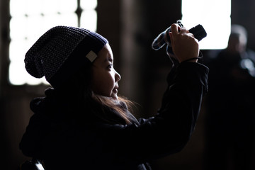 Young Asian tourist taking picture in dark temple. Low key photography with rim lighting