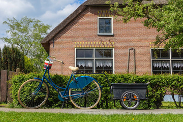 Parking bike with trolley in front of the house with brick wall, classic living in Giethoorn