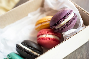 Assorted colorful french macaroons cardboard box on rustic wooden table