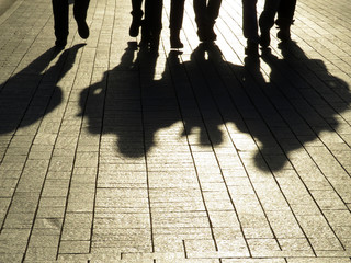 People silhouettes and shadows on the street. Crowd walking down on sidewalk, concept of strangers,...