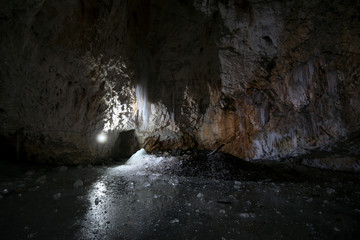 Underground glacier in Glaciers Cave in Apuseni mountains, Scarisoara, Romania. Big icicles holding...