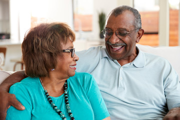 Senior black couple sitting at home, smiling at each other, close up