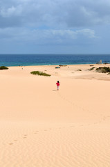 Child walks along the beach to the ocean. Dunas de Corralejo, Fuerteventura island