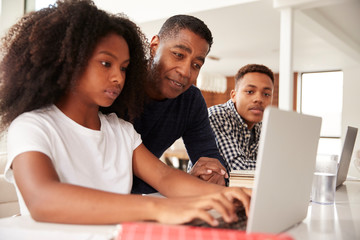 Middle aged black dad helping his teen kids with homework, low angle, close up