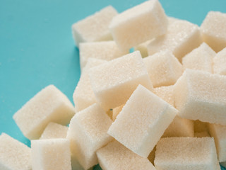 Background of sugar cubes. White cube sugar on blue background. White sugar close up