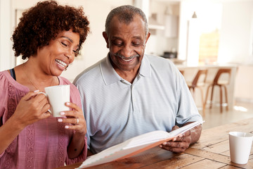 Middle aged black woman and her dad looking through photo album together at home, close up