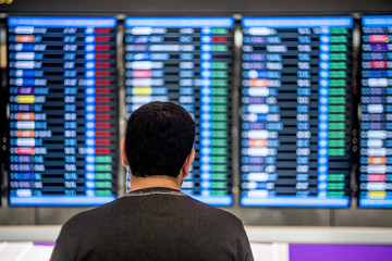 Fototapeta premium Man looking at the flights details board at the airport