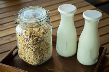 Cereal and milk in classic retro containers on wooden platter. Served in the morning for good health
