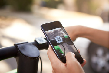 Close up of woman's hands using smartphone while riding on an electric scooter,detail