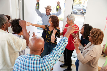 Millennial black couple arriving at a family party with gifts and champagne, elevated view