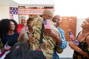Millennial black soldier returning home to his family, embracing grandfather, back view