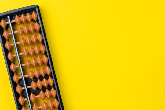 Small abacus mathematic toy on vivid yellow background with copy space, math, finance or school concept