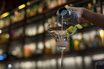 Bartender's hand pouring cocktail into cocktail glass