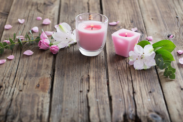 Fototapeta na wymiar pink candles and flowers on wooden background