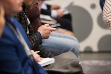 business people hands typing on smart phone during the seminar at conference room