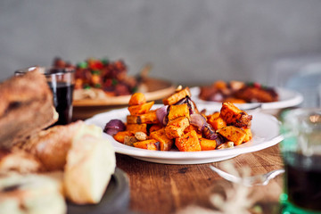 Low angle view of table served with traditional British Sunday roast dinner, featuring roasted chicken, squash and sweet potatoes