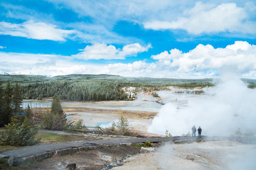Stream coming out before massive amount of hot stream burst out with trees and snow mountain background at Yellowstone National Park