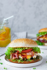 Homemade fresh chicken burger with bacon on gray plate on white background with lemonade, Fast food at summer time