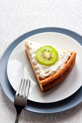 Homemade cottage cheese cake with kiwi fruit and cream on a plate