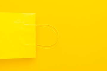 shopping paper bag on the yellow background with copy space. flat lay photo of upturned yellow bag. summer sale concept