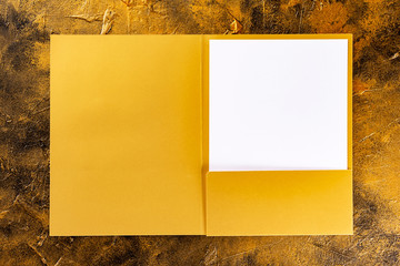 Corporate stationery set mockup. Golden foil presentation folder and letterhead at golden textured background.