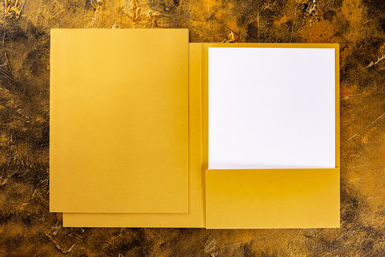 Corporate stationery set mockup. Golden foil opened and closed presentation folders and letterhead at golden textured background.