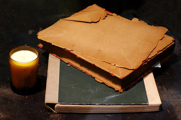 Harsh dark lighting still life art of old papers on old book and a cup of candle light