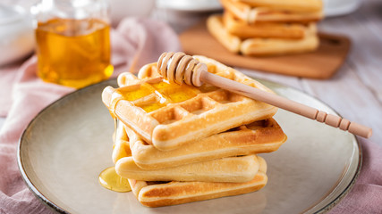 Waffles with honey on a light background.