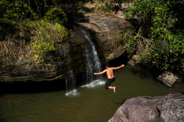 Asian boy jumps from cliff into river