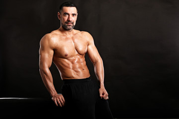 Fototapeta premium Portrait of young handsome muscular bodybuilder on black background 