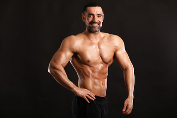 Fototapeta na wymiar Portrait of young handsome muscular bodybuilder on black background 