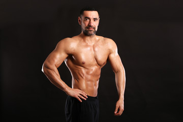 Fototapeta na wymiar Portrait of young handsome muscular bodybuilder on black background 