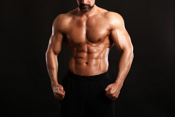 Fototapeta na wymiar Portrait of young handsome muscular bodybuilder on black background torso close up view 