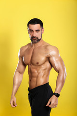 Portrait of young handsome  muscular bodybuilder on yellow background 
