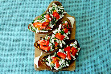 Toasts with white cheese and herbs with garlic on a small wooden board. Open sandwiches with selenium and cottage cheese. Garlic toast with grated mozzarella cheese and greens. 