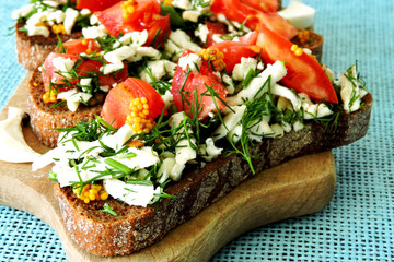 Toasts with white cheese and herbs with garlic on a small wooden board. Open sandwiches with selenium and cottage cheese. Garlic toast with grated mozzarella cheese and greens. 