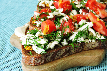 Toasts with white cheese and herbs with garlic on a small wooden board. Open sandwiches with selenium and cottage cheese. Garlic toast with grated mozzarella cheese and greens. 