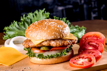 Cheese burger with ingredients on wooden platter