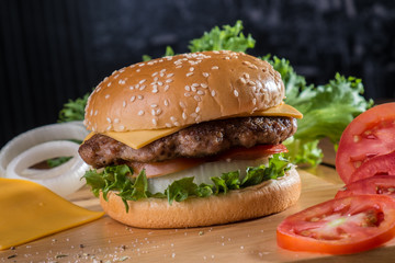 Cheese burger with ingredients on wooden platter