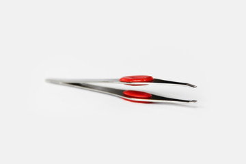 designer metal tweezers with red plastic insert on a white background