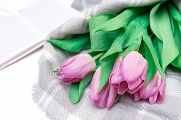 Bouquet of cut pink lilac tulips with a notebook on white background close up