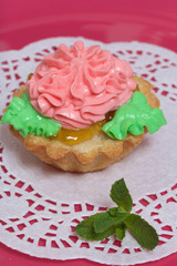 Basket cake decorated with cream of different colors. Stuffing from jam. Decorated with mint leaves.