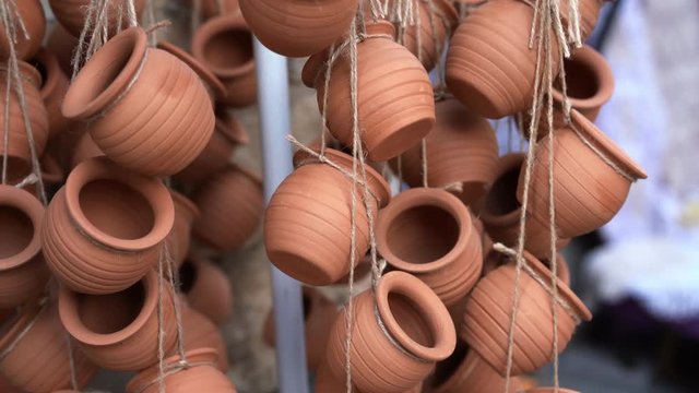 Closeup of clay ceramic pots hanging on ropes and fluttering on wind