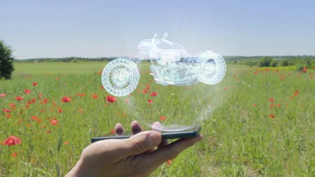 Hologram of road bike on a smartphone. Person activates holographic image on the phone screen on the field with blooming poppies